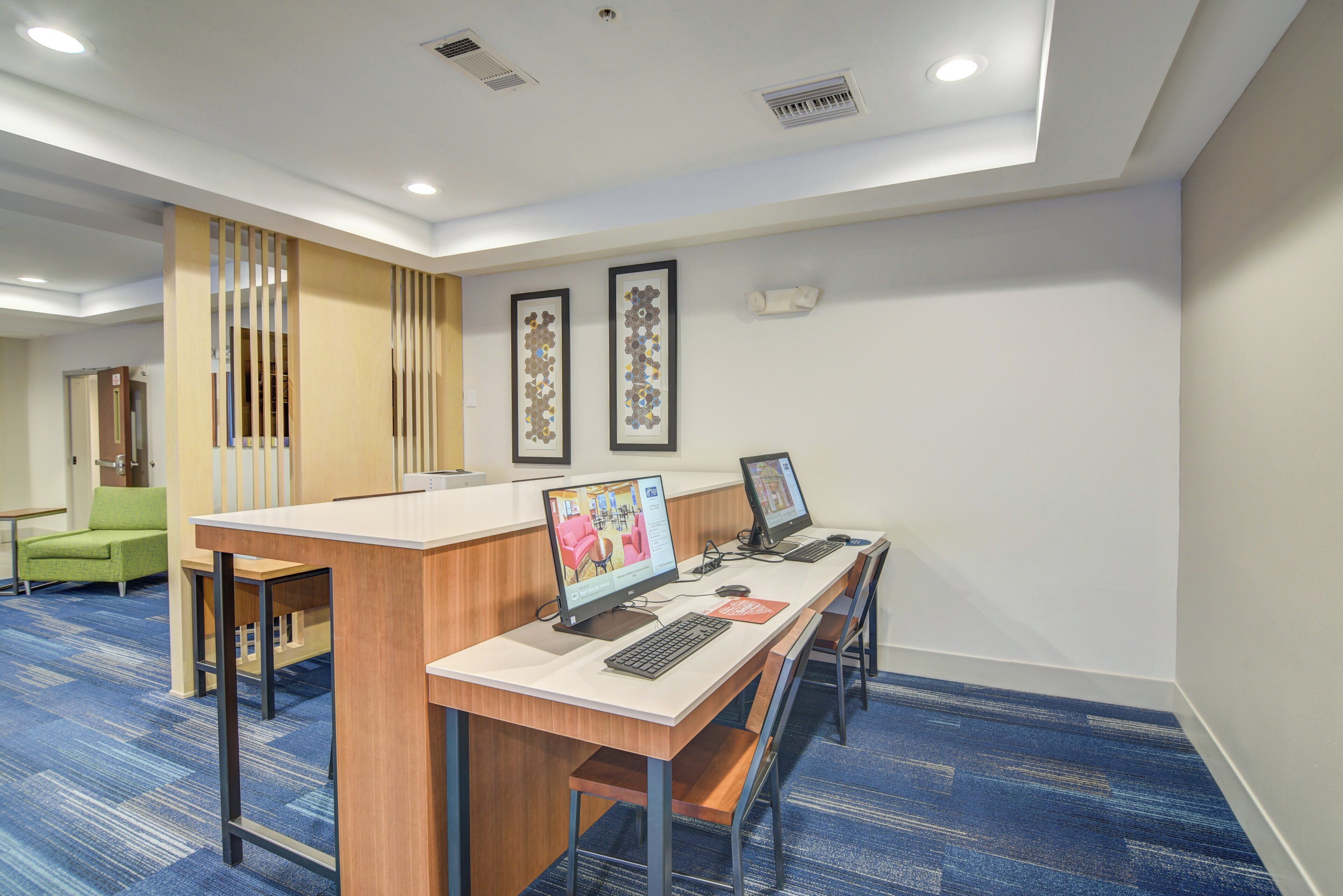 A reception area with a desk, two computers, and a seating area with chairs.