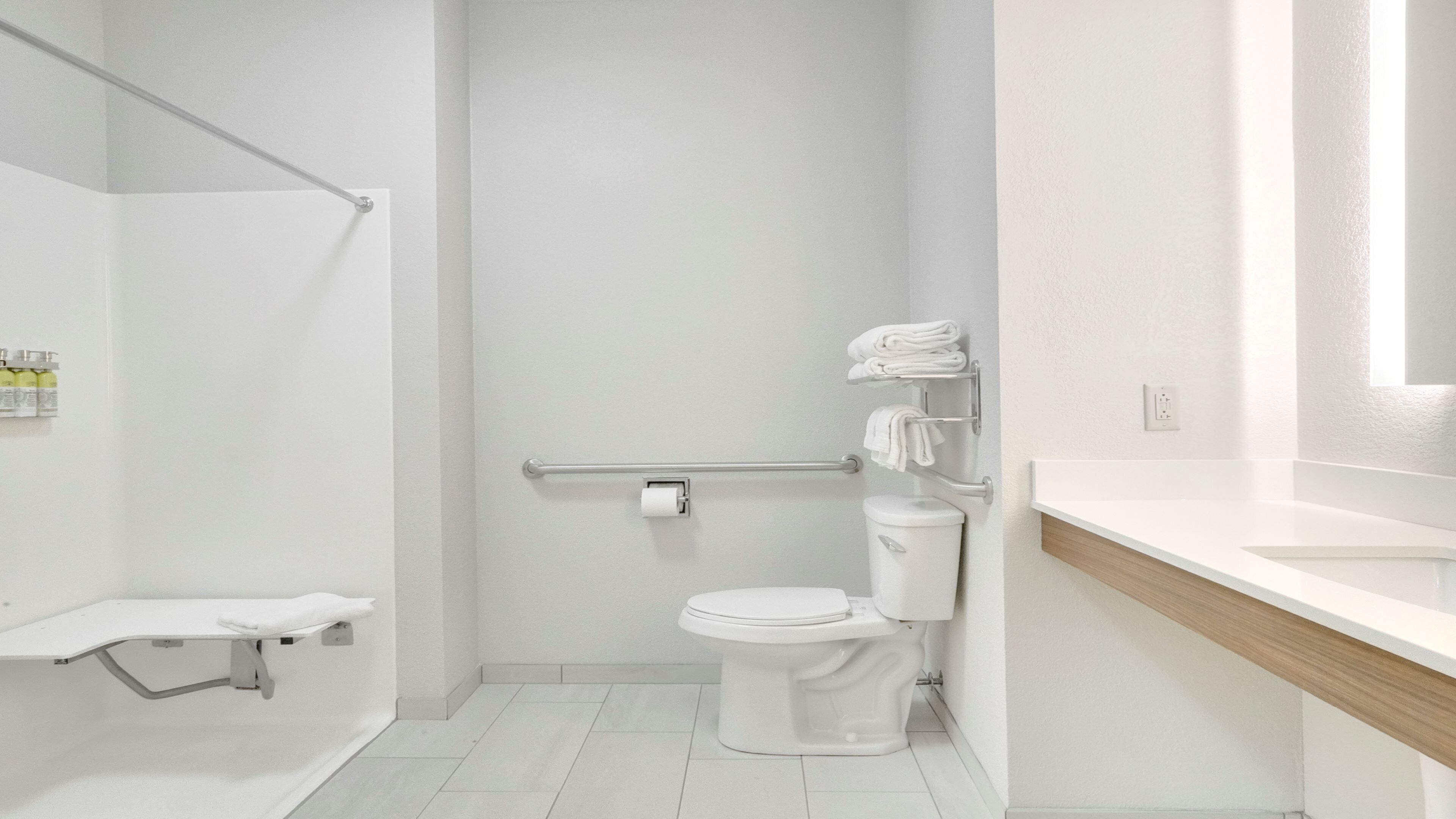 Un baño moderno con inodoro, zona de ducha y tocador con espejo.