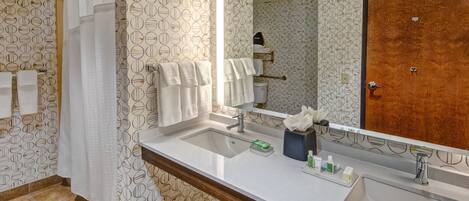 A bathroom with a large mirror, two sinks, and a wooden door.