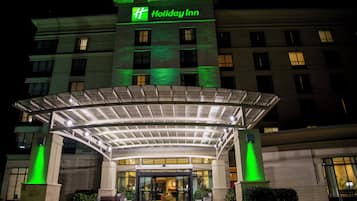 A Holiday Inn hotel with a covered entrance, multiple floors, and a prominent green sign.