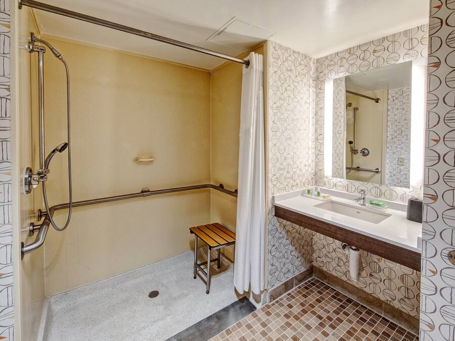 A bathroom with a shower, a sink, and a mirror.