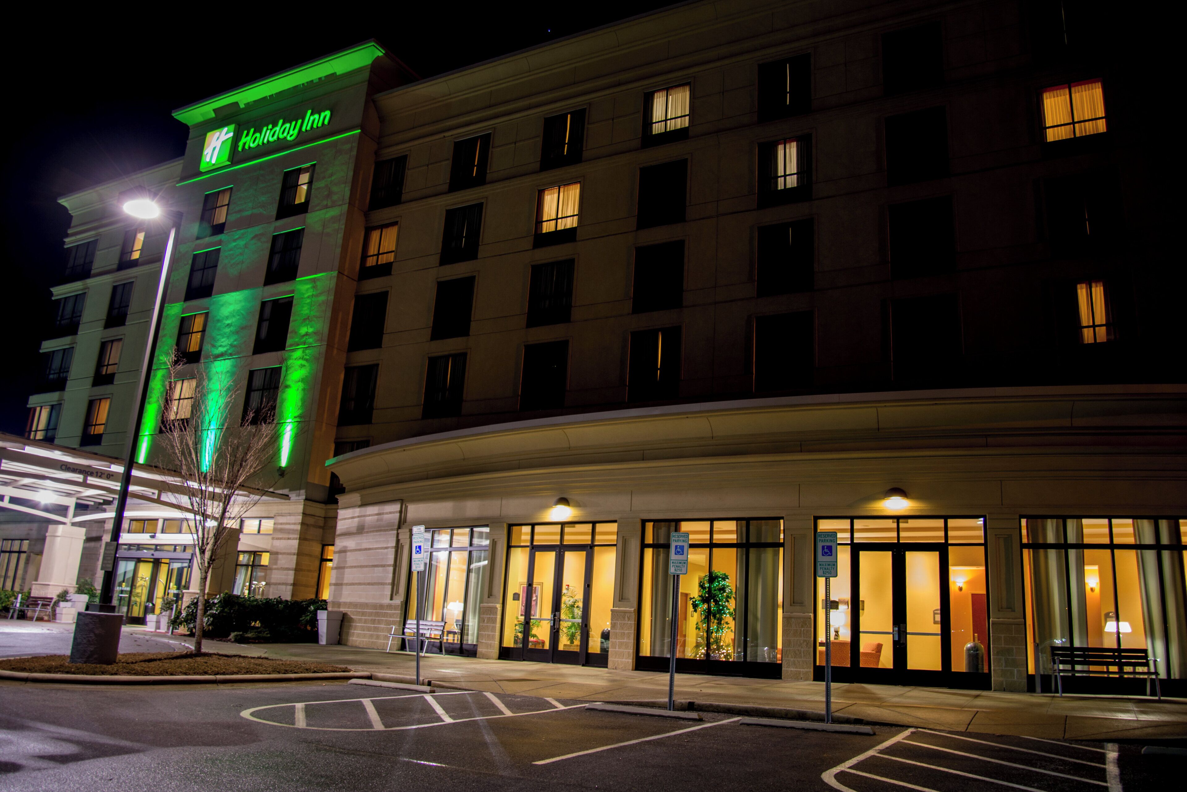 Un hôtel Holiday Inn avec une entrée bien visible, un parking et une façade bien éclairée.