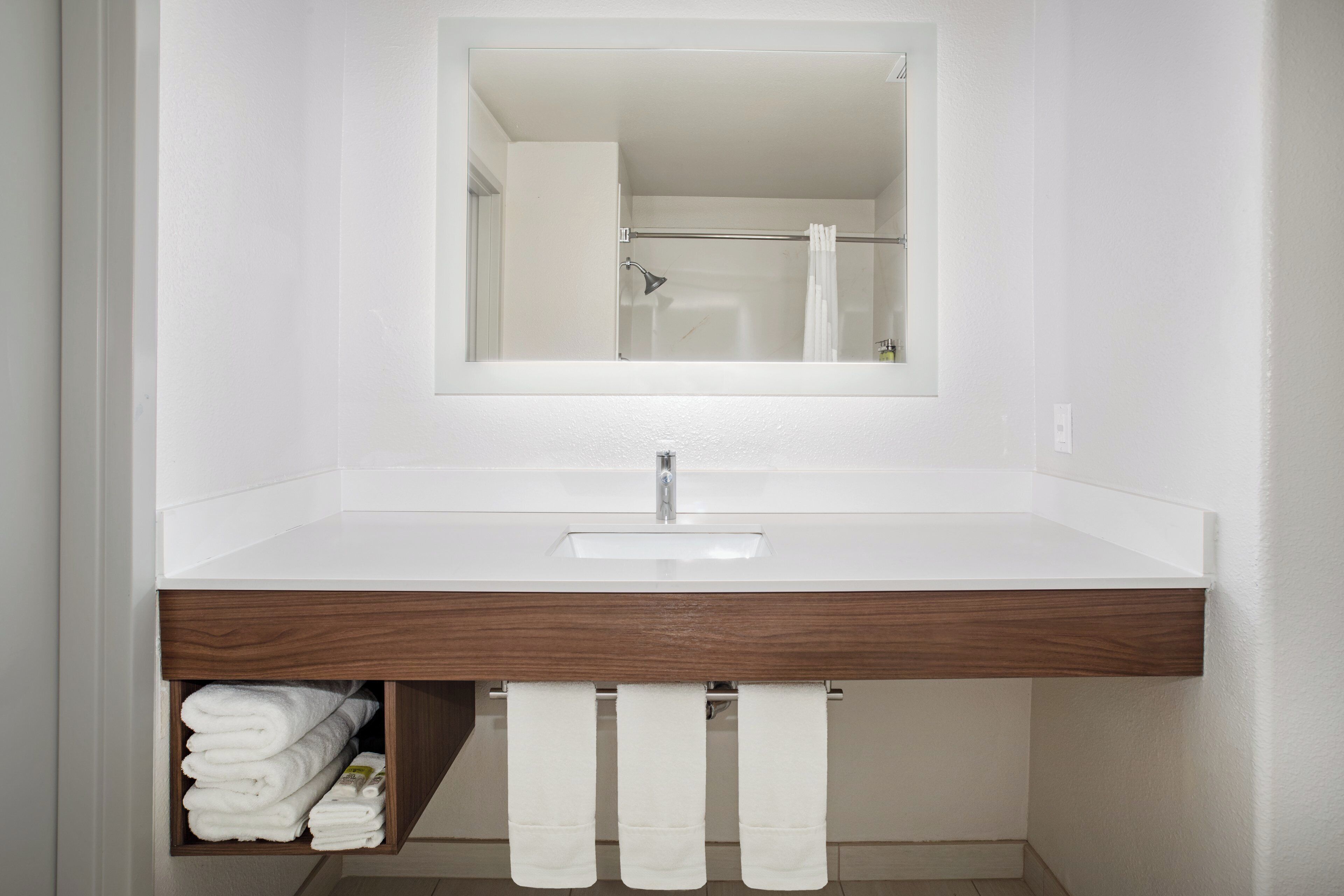 A bathroom with a white sink, a mirror, and a towel rack.
