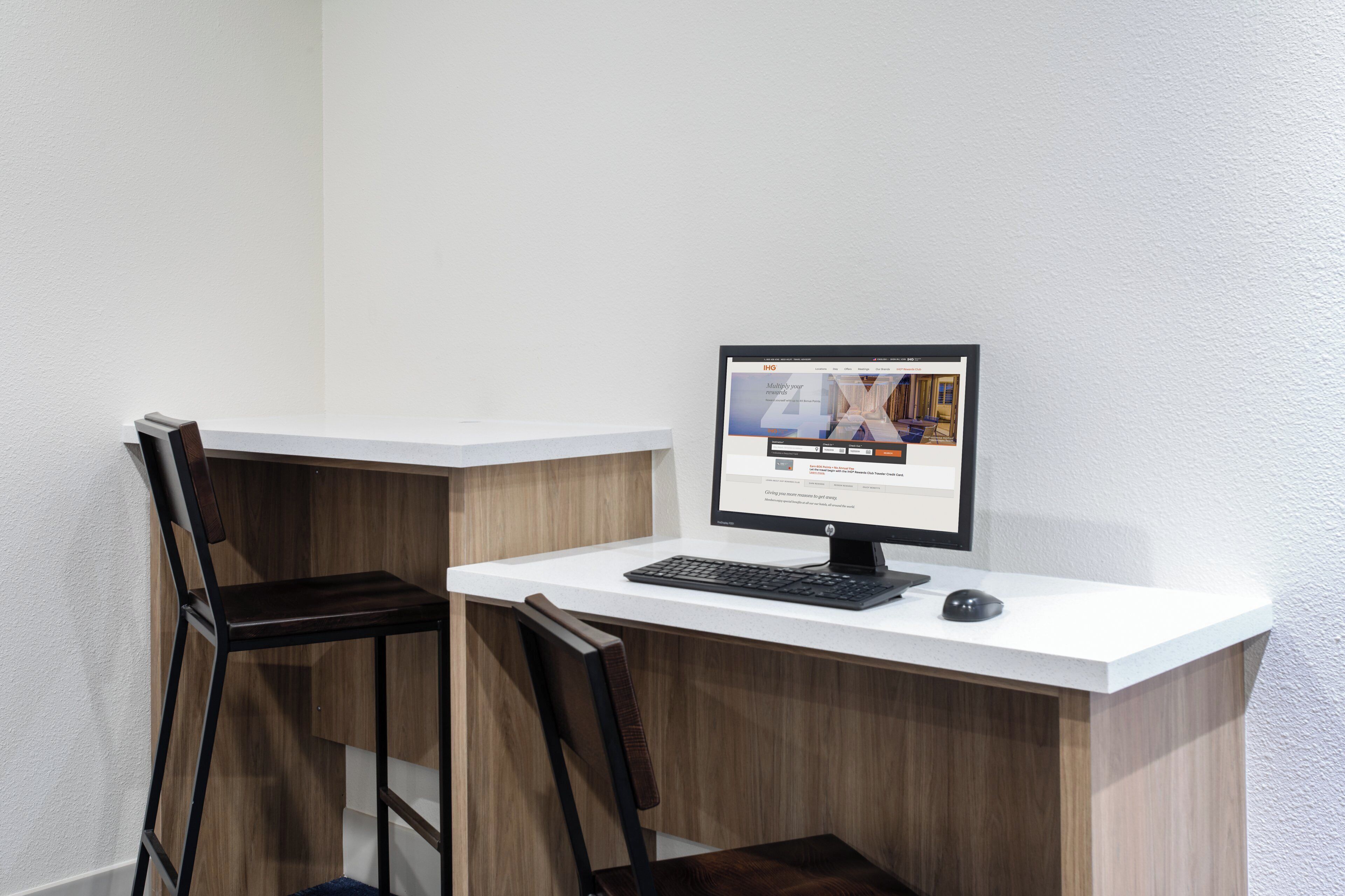 Um pequeno espaço de escritório com uma mesa, um computador e duas cadeiras.