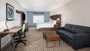 A hotel room with a bed, a desk with a chair, a sofa, a TV, and a framed picture on the wall. - Holiday Inn Express & Suites Chowchilla - Yosemite Park Area by IHG (Chowchilla)