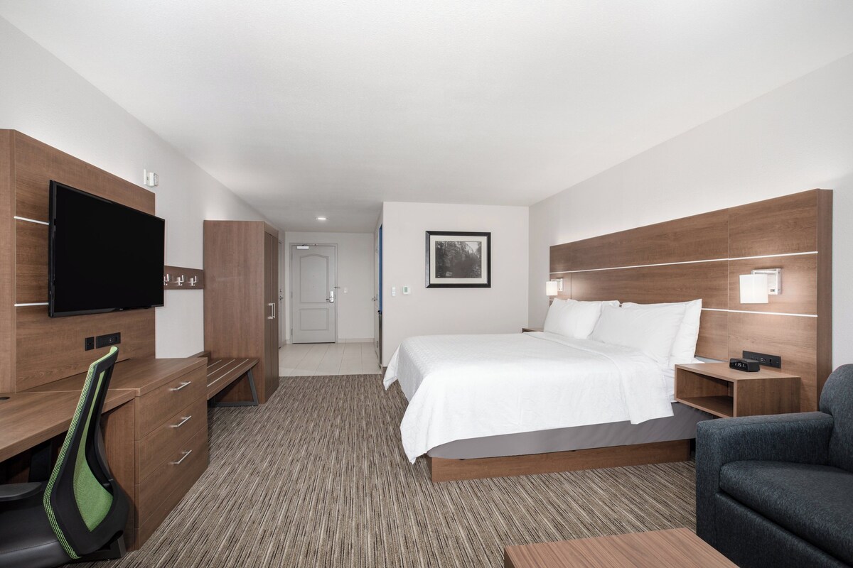 Une chambre d’hôtel équipée d’un lit, d’une télévision, d’un bureau, d’une chaise et d’une table de chevet.