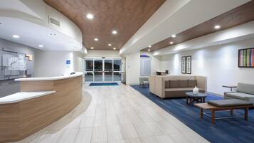 A reception area with a curved reception desk, a waiting area with a sofa and chairs, and a reception desk with a computer.