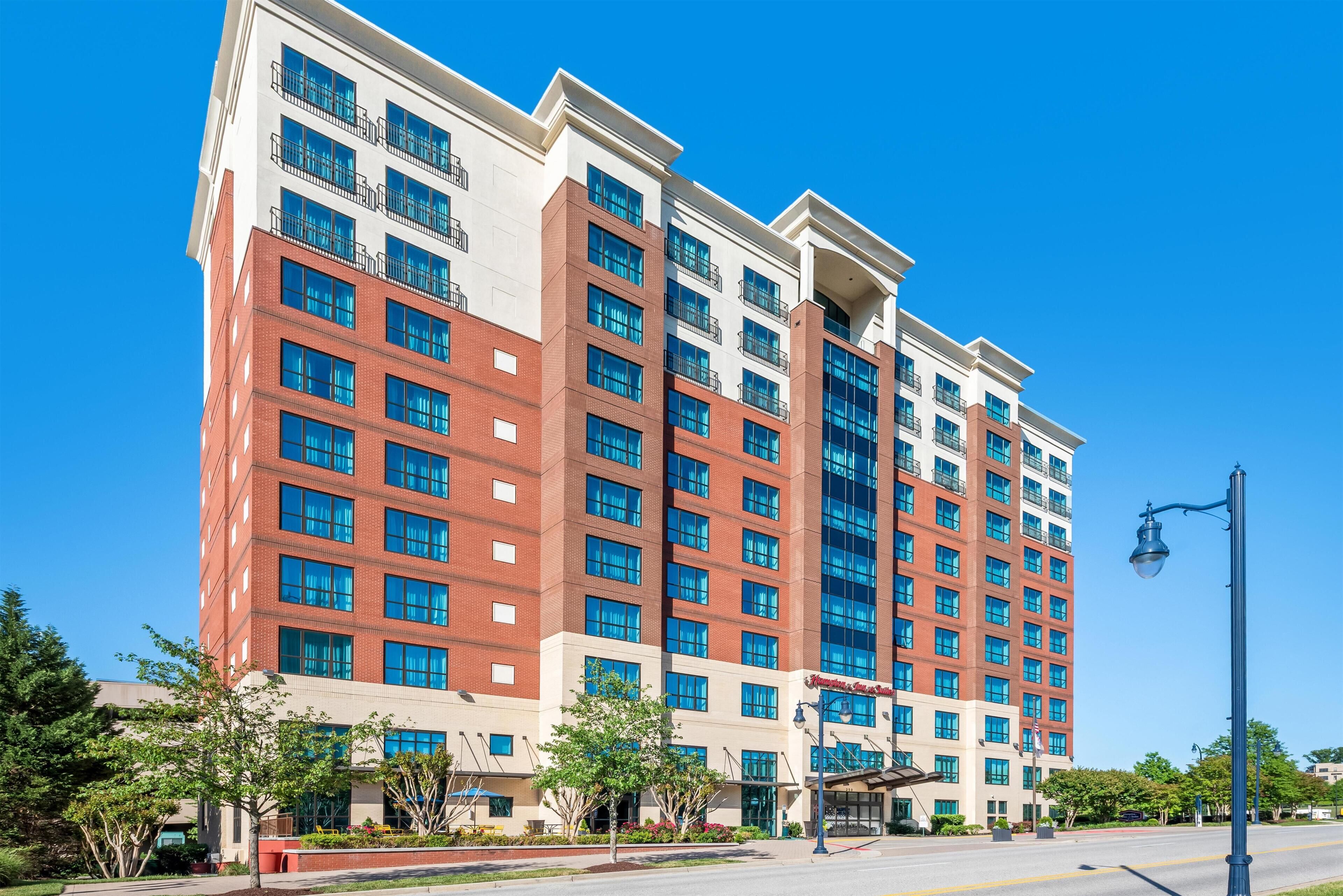 A multi-story hotel with a modern architectural design, featuring a mix of brick and glass facades, and a prominent entrance with a covered area.