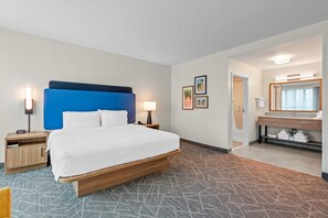 A hotel room with a bed, bedside tables, a bathroom with a mirror, and a patterned carpet. - Hampton Inn & Suites National Harbor - Alexandria Area (Oxon Hill)