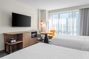 A hotel room with a bed, a desk with a flat-screen TV, a microwave, and a small table with chairs. - Hampton Inn & Suites National Harbor - Alexandria Area (Oxon Hill)