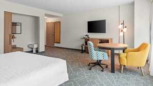 A hotel room with a bed, a desk, a chair, a television, and a lamp. - Hampton Inn & Suites National Harbor - Alexandria Area (Oxon Hill)
