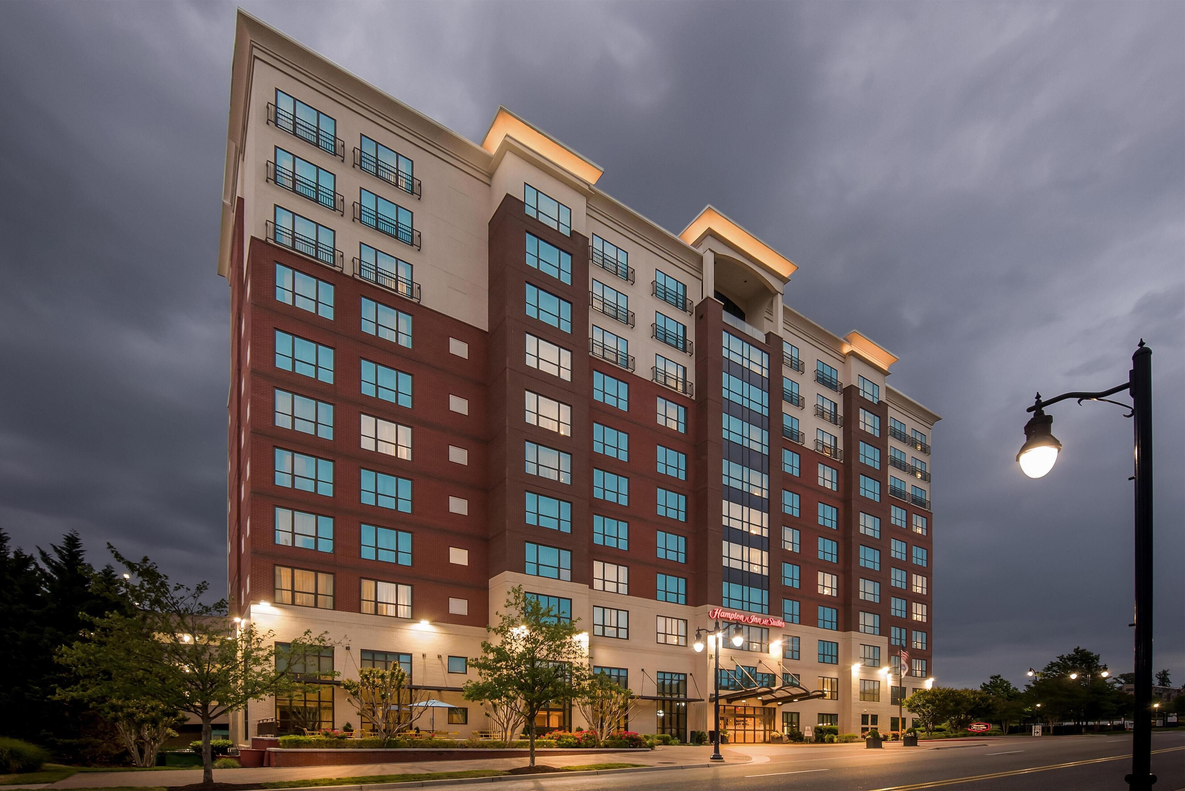 A multi-story hotel building with a modern architectural design, featuring a mix of brick and glass facades, and a well-lit entrance area.
