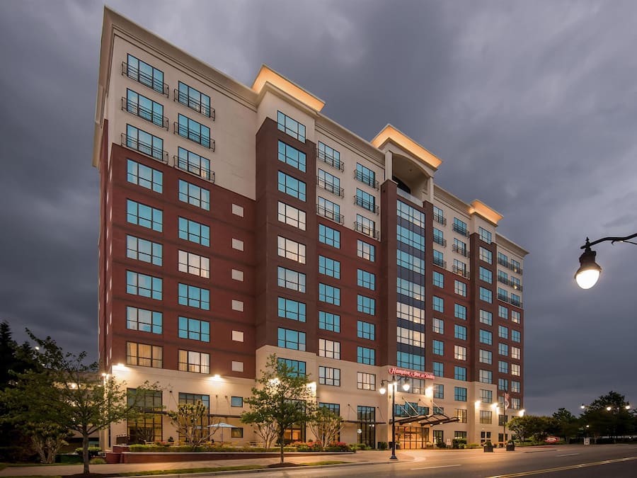 A multi-story hotel building with a modern architectural design, featuring a mix of brick and glass facades, and a well-lit entrance area.