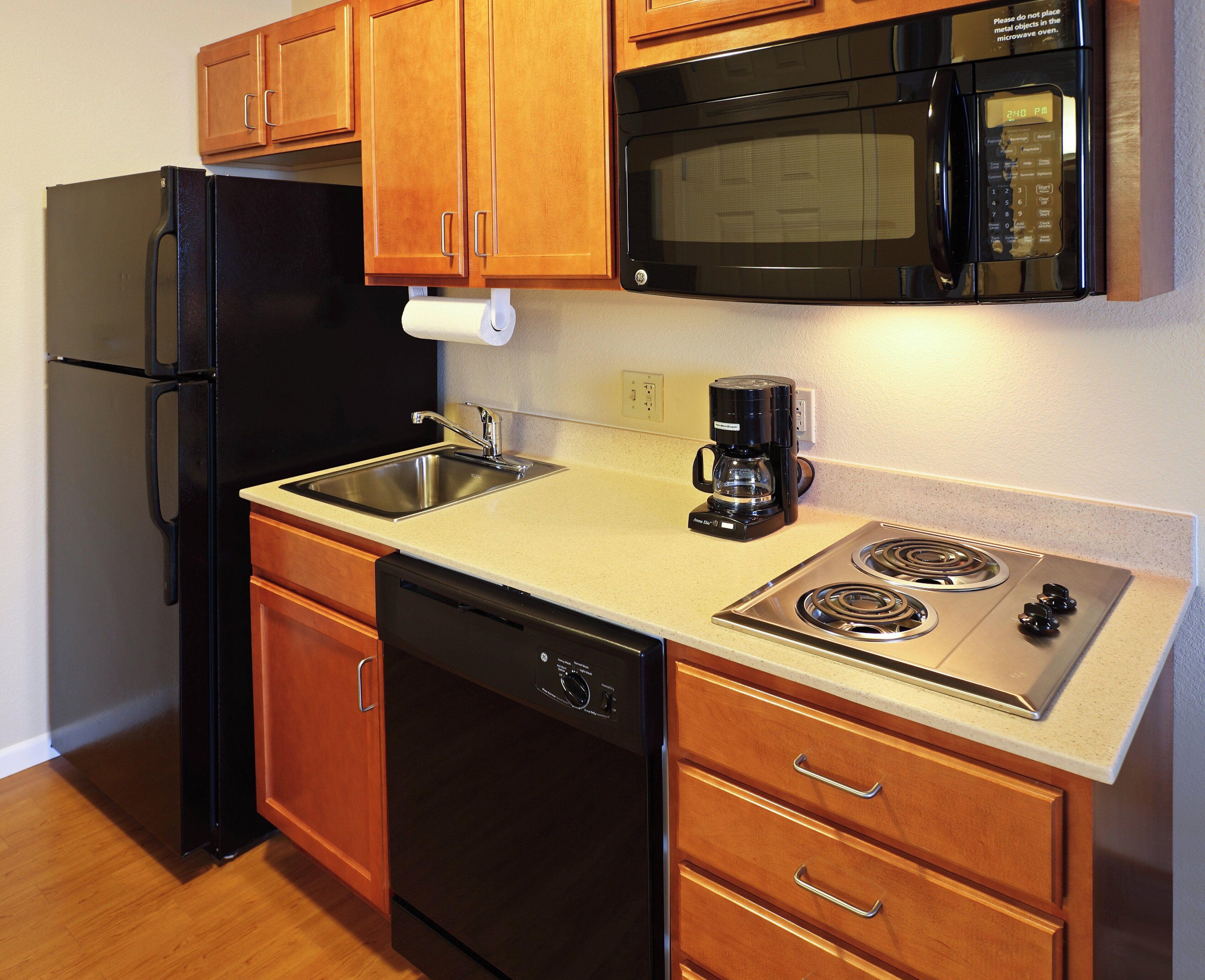 A compact kitchen with a refrigerator, microwave, stove, sink, and dishwasher.