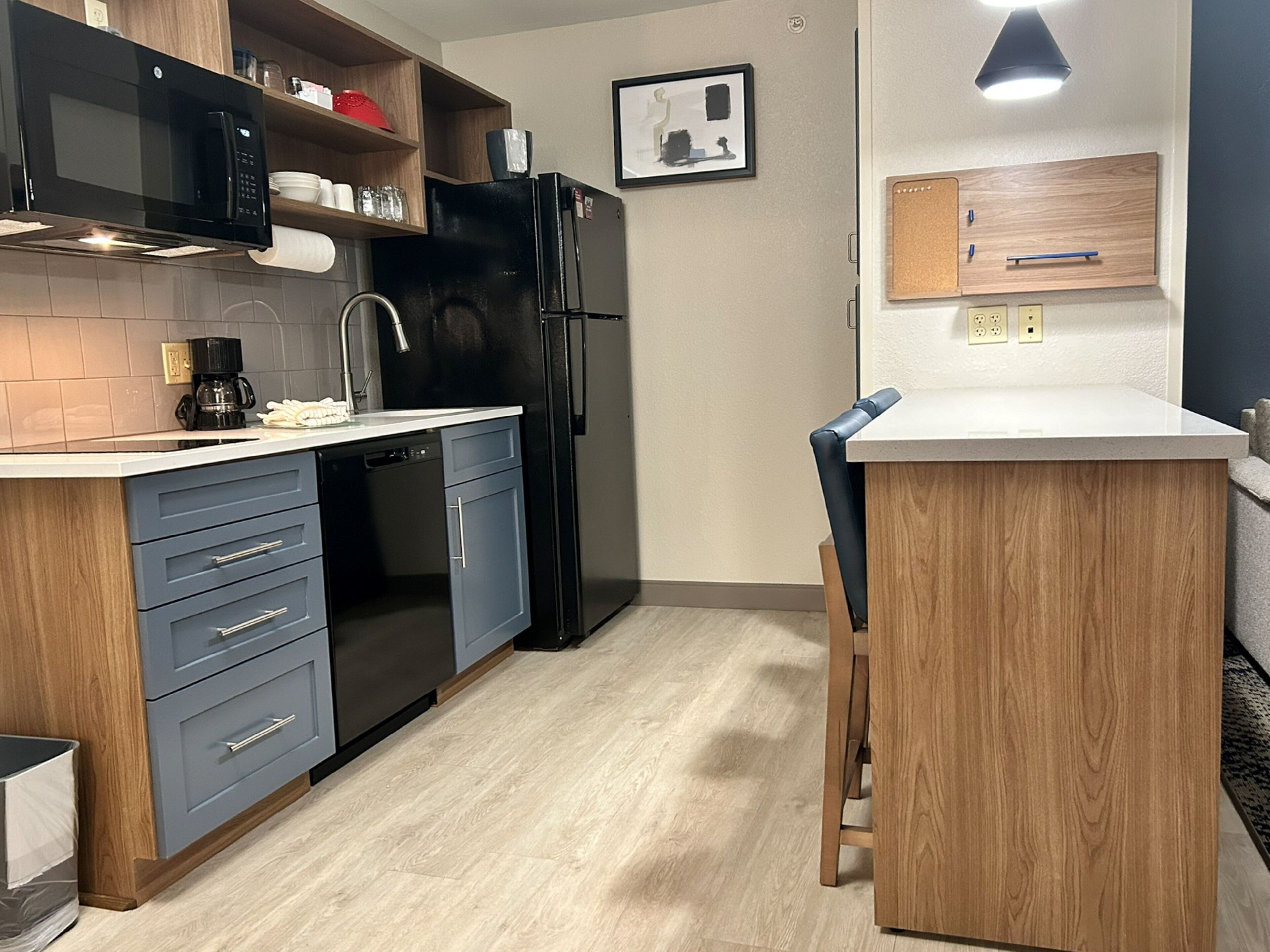 Una cocina moderna con lavavajillas integrado, un refrigerador negro y una encimera de madera.