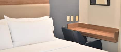 A hotel room with a bed, a desk, and a chair.