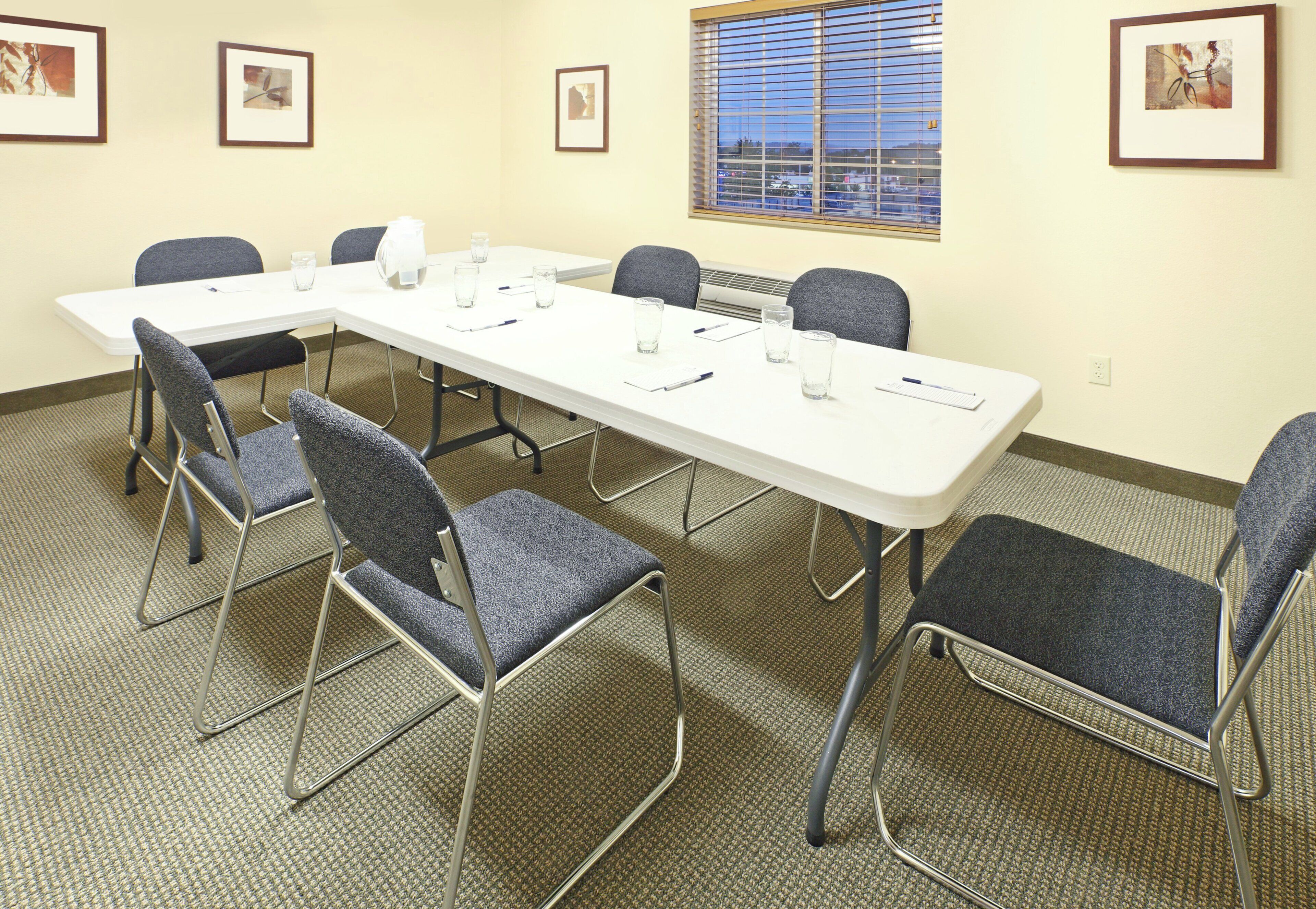 A conference room with a long table, six chairs, and framed pictures on the walls.