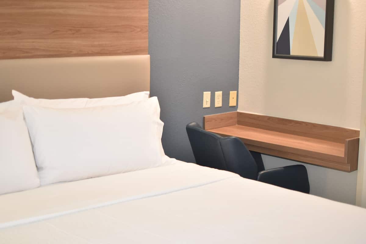 Ett hotellrum med en säng, ett skrivbord och en stol.