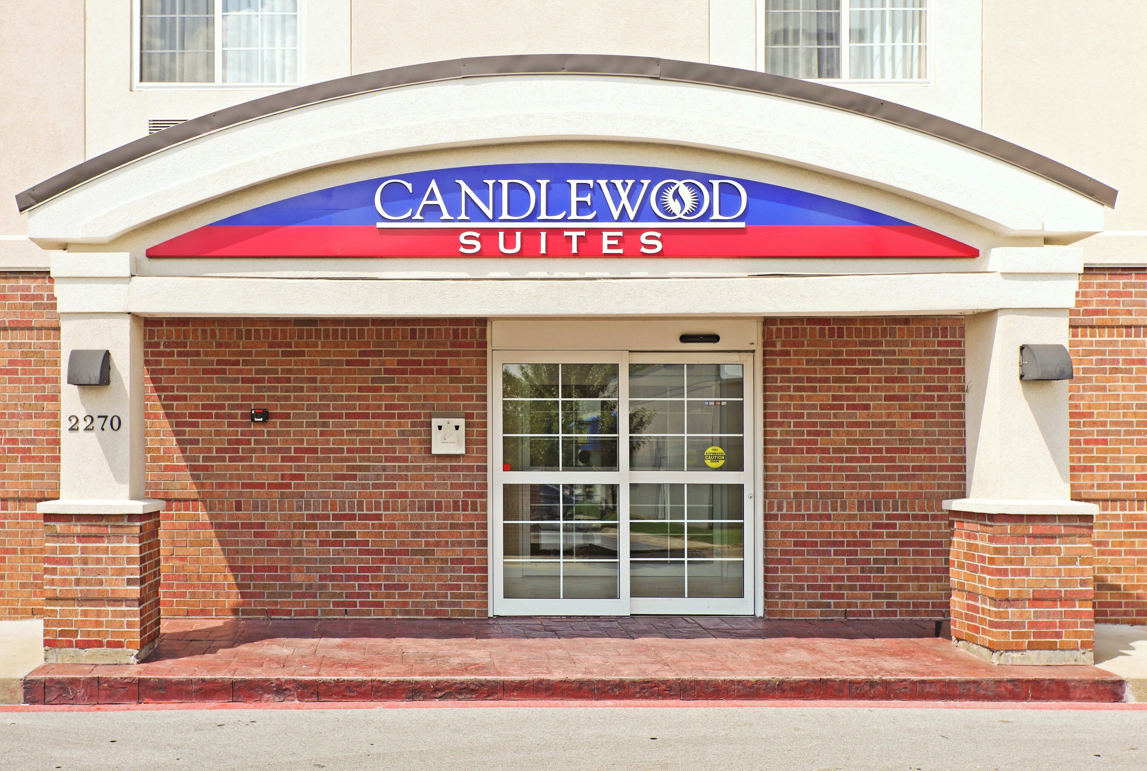 A hotel entrance with a sign reading 'CANDLEWOOD SUITES' above a glass door.