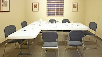Un salón de conferencias con una larga mesa, seis sillas e imágenes enmarcadas en las paredes.