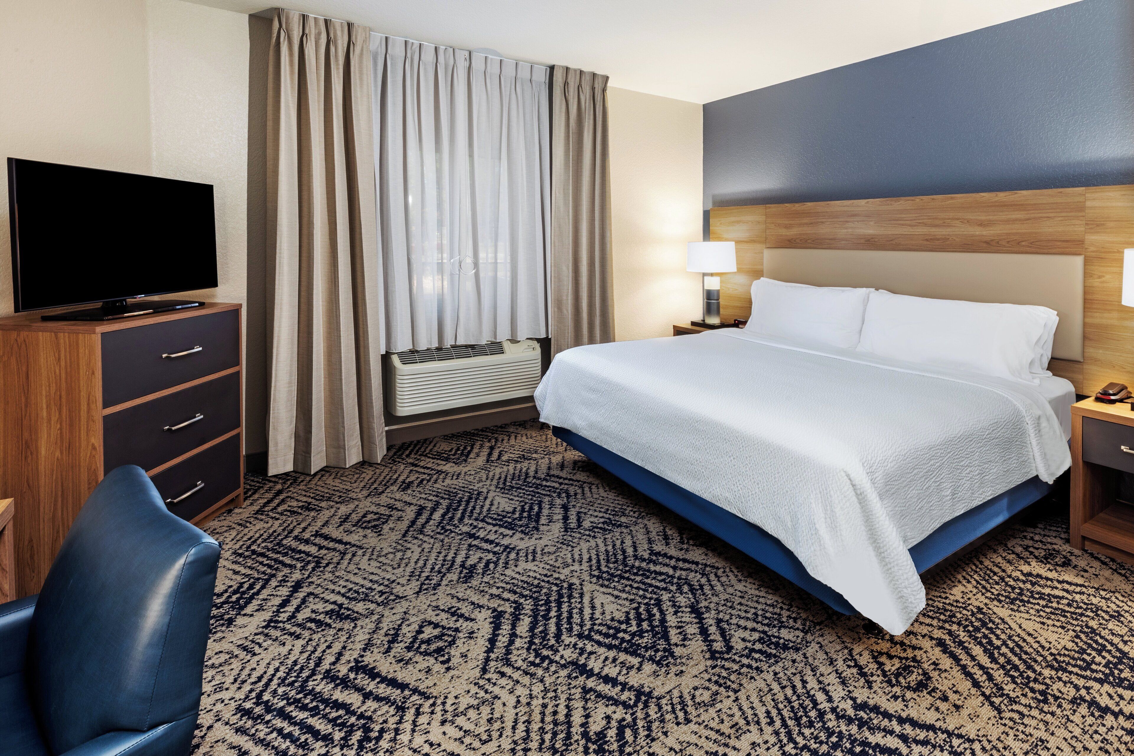 Une chambre d’hôtel avec un lit, une télévision, un bureau et une chaise.