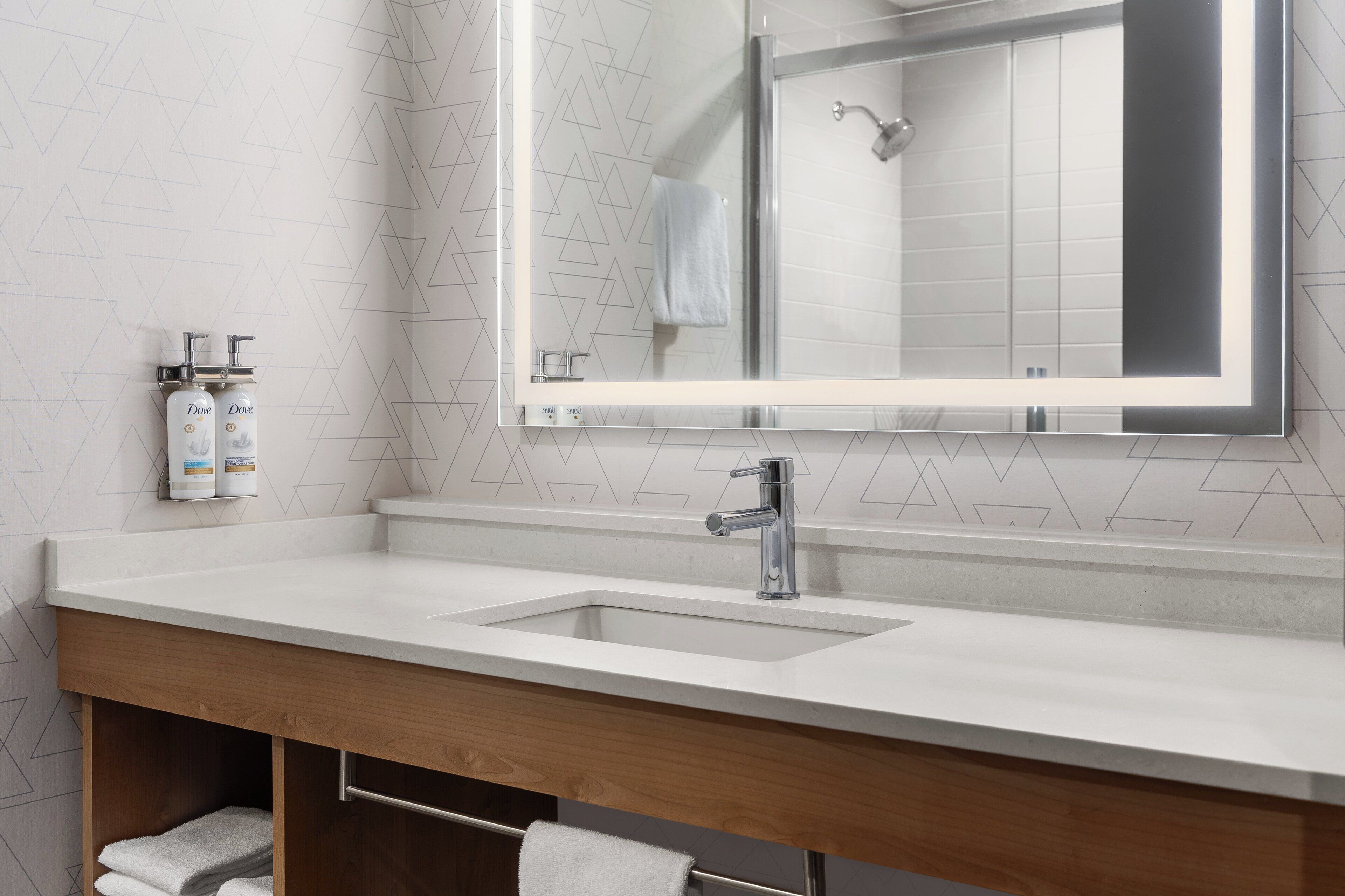 A modern bathroom with a double sink, a large mirror, and a shower.