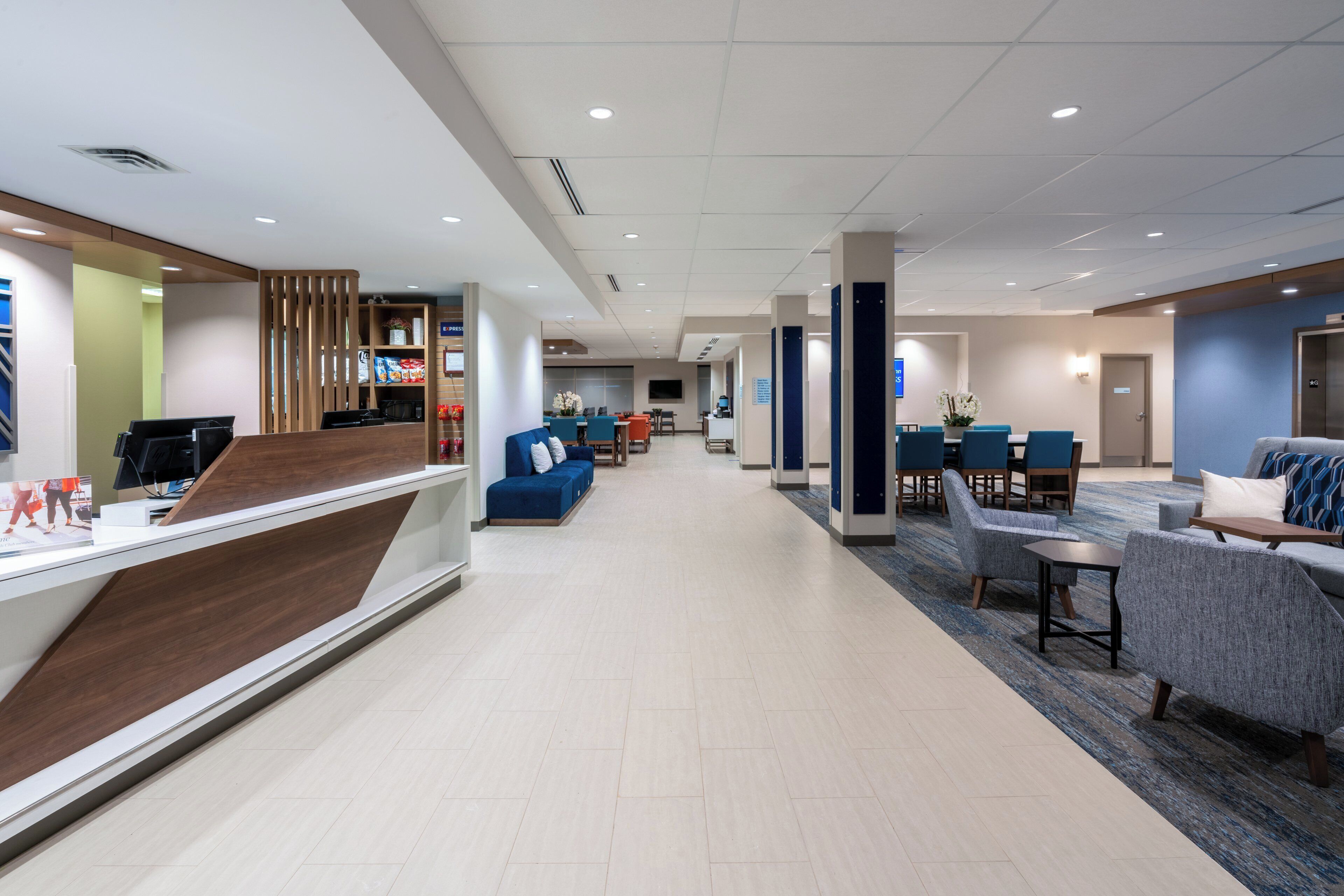 A hotel lobby with a reception desk, seating area, and a TV screen.