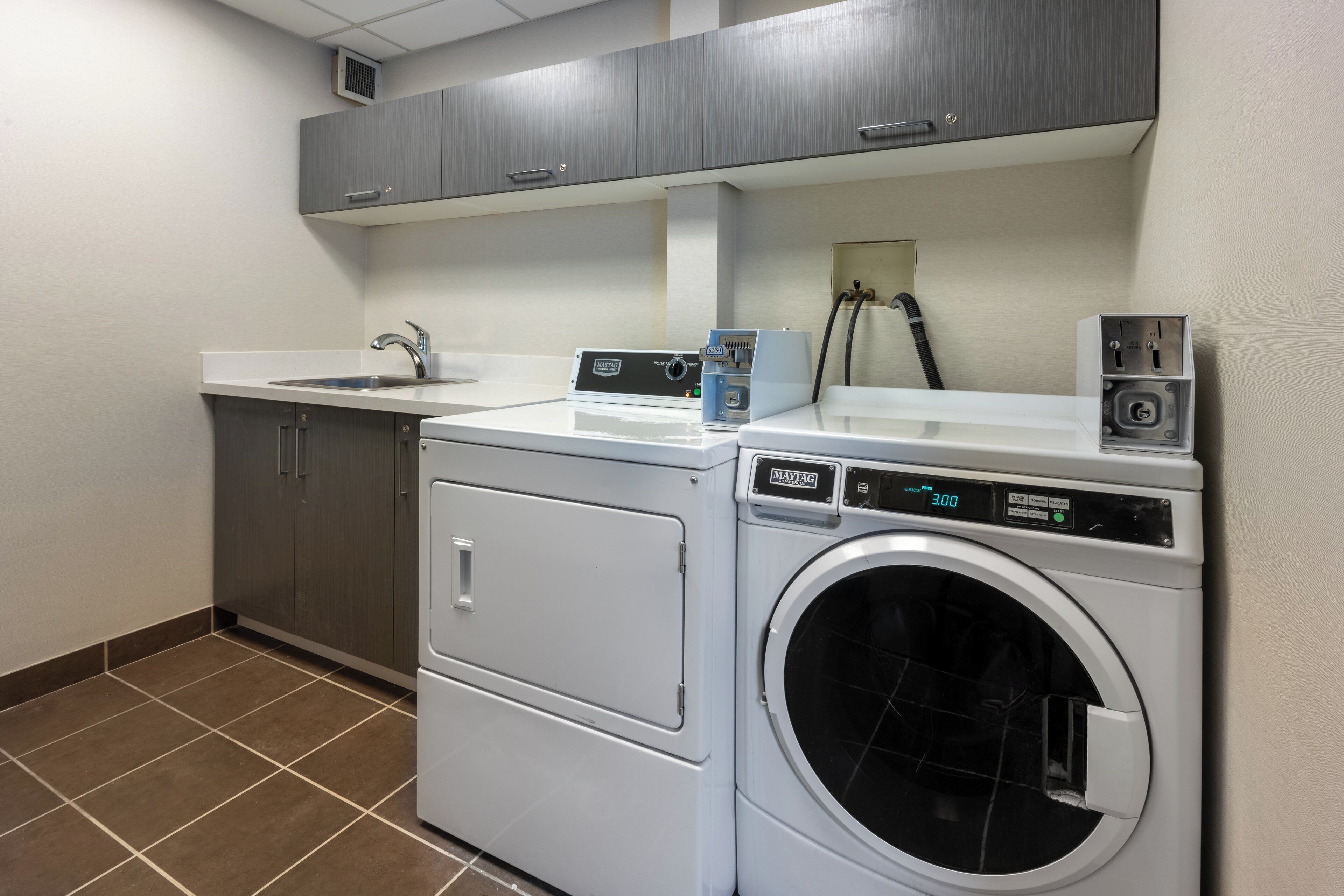A laundry area with a washing machine, dryer, and cabinets.