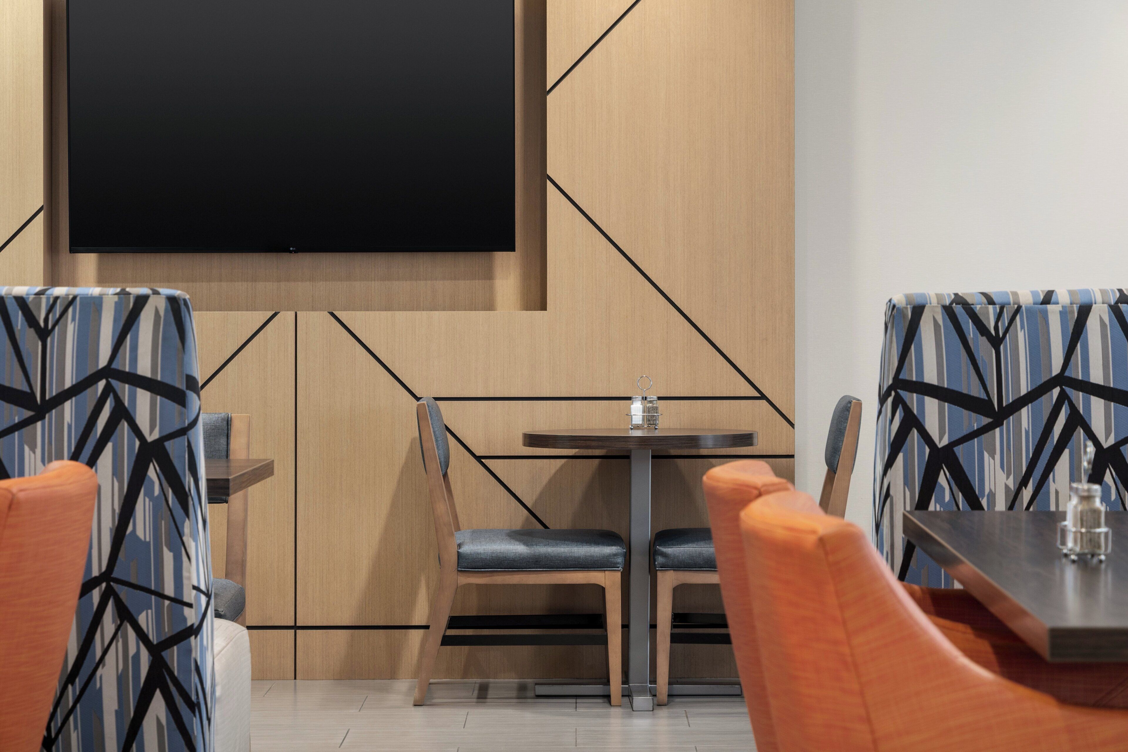 Un comedor moderno con televisor de pantalla plana, paneles de madera y asientos tapizados con diseño.