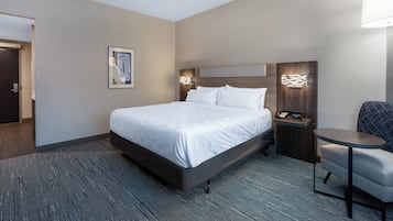 Habitación de hotel con una cama grande, mesita de noche con un teléfono y una pequeña mesa redonda.