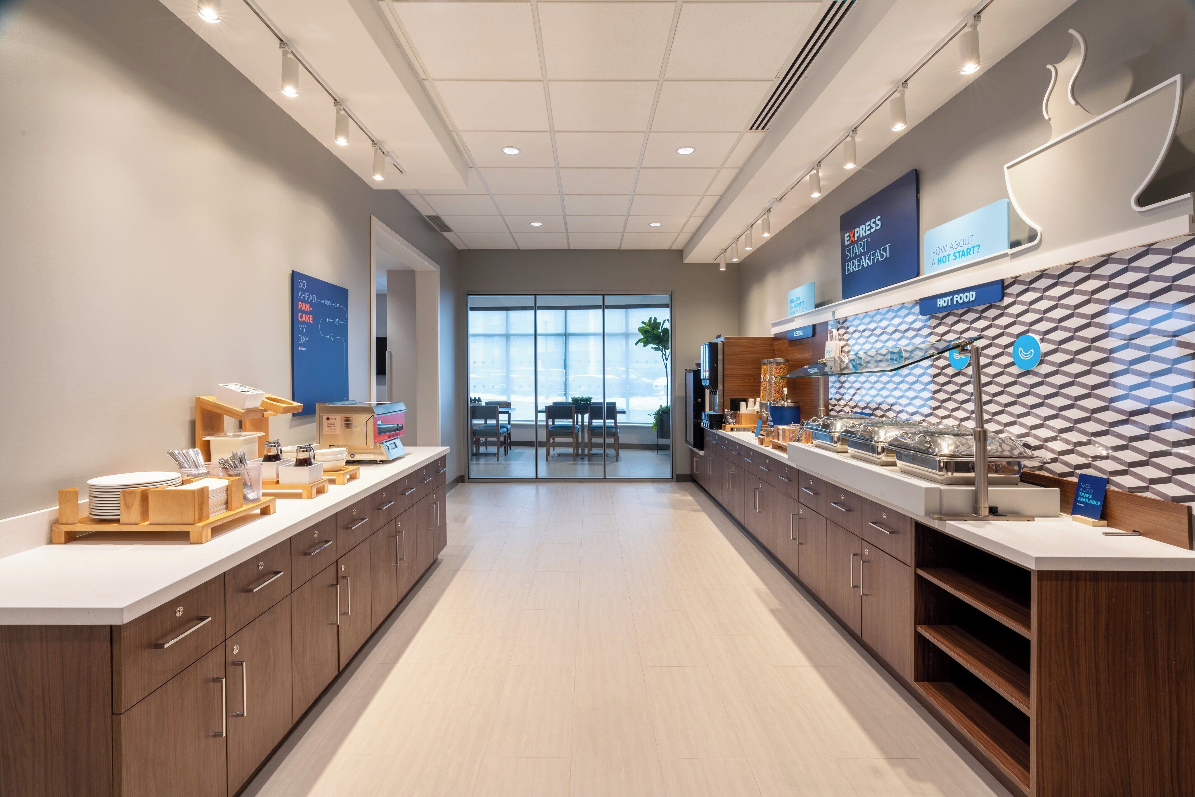 A modern breakfast area with a long counter, wooden cabinets, and a view of the dining area.