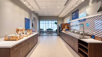 A modern breakfast area with a long counter, wooden cabinets, and a view of the dining area.