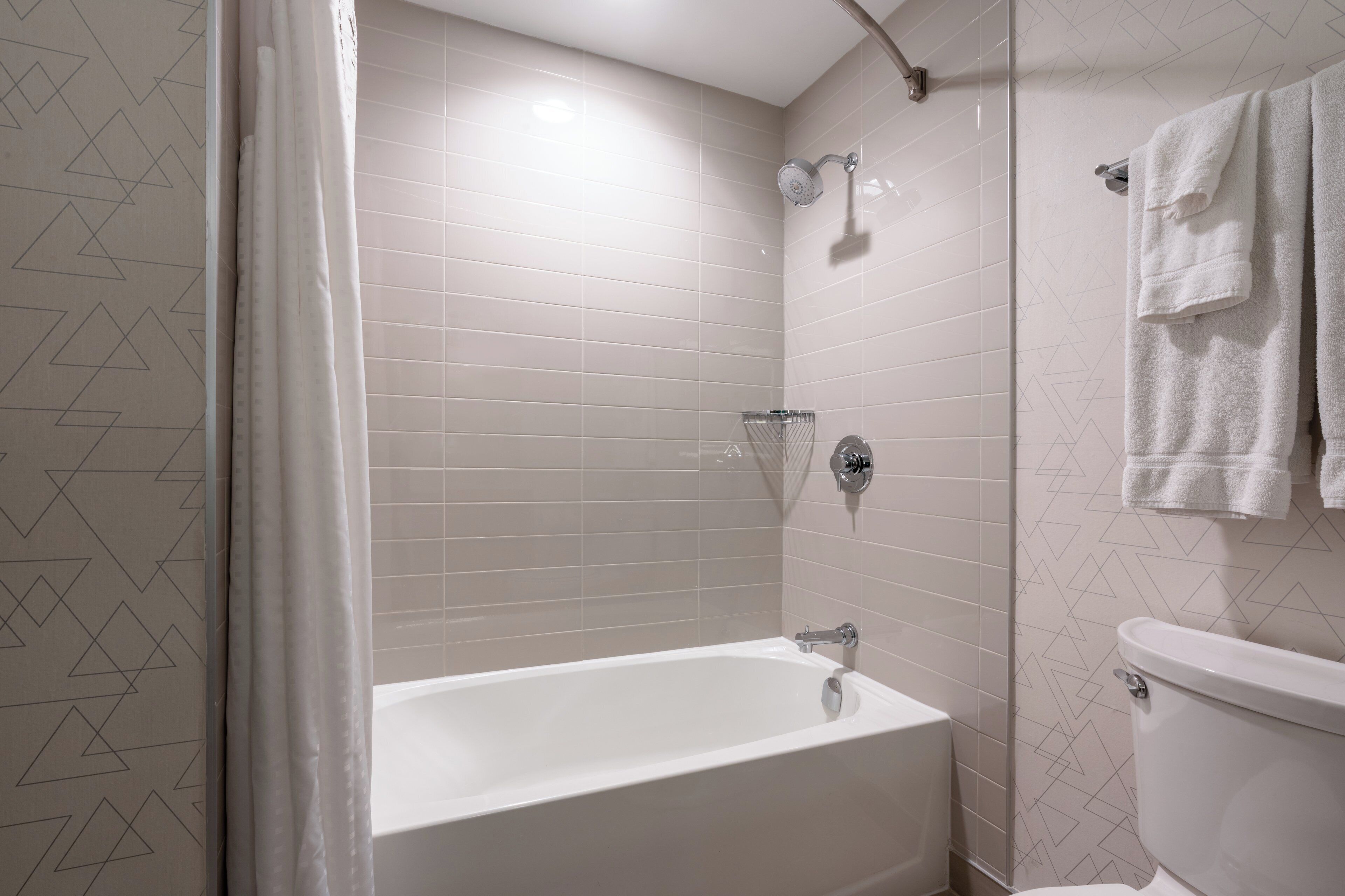 A bathroom with a bathtub, shower, and toilet.