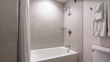 A bathroom with a bathtub, shower, and toilet.