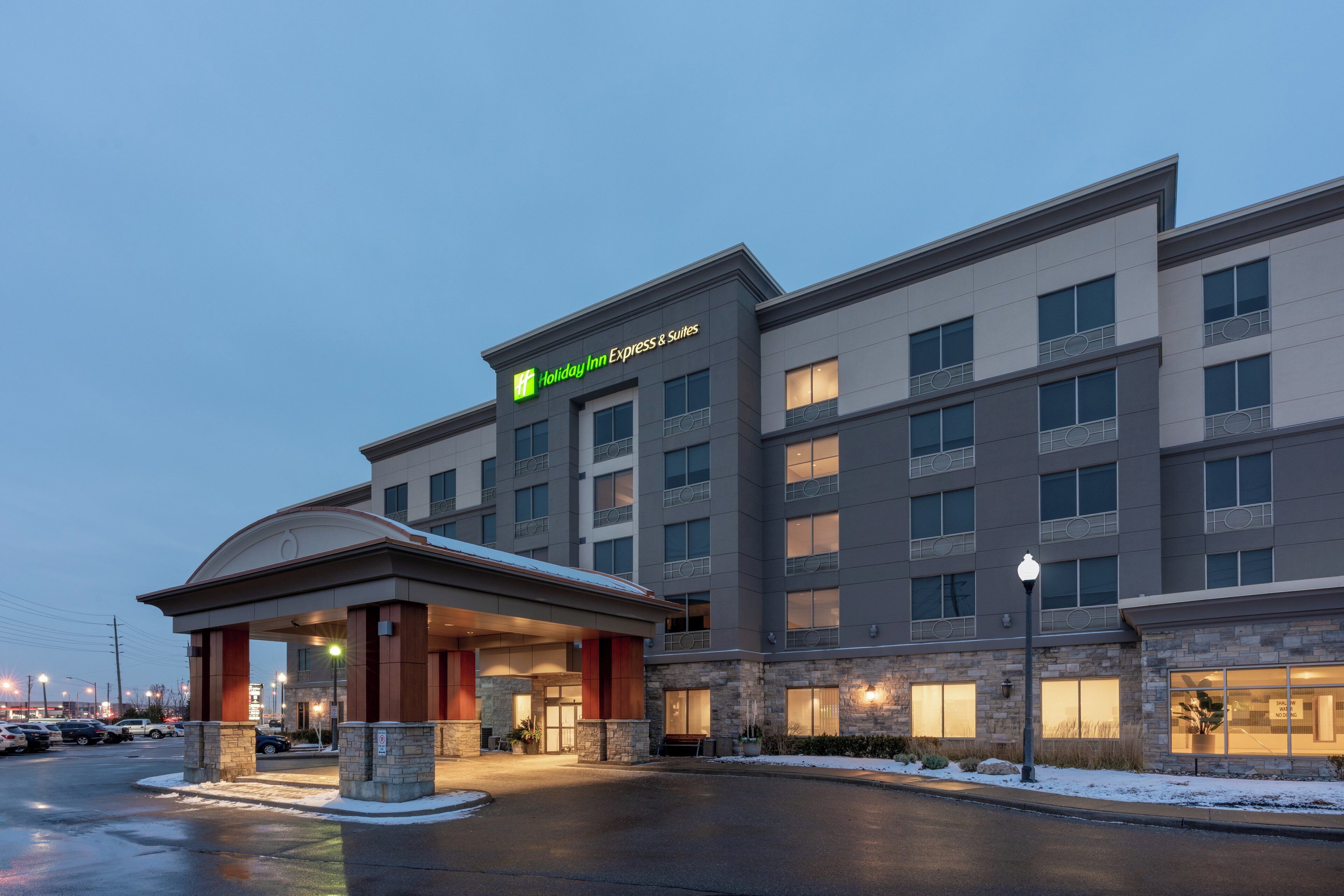 Edificio de Holiday Inn Express & Suites con entrada techada, varios pisos y un estacionamiento.
