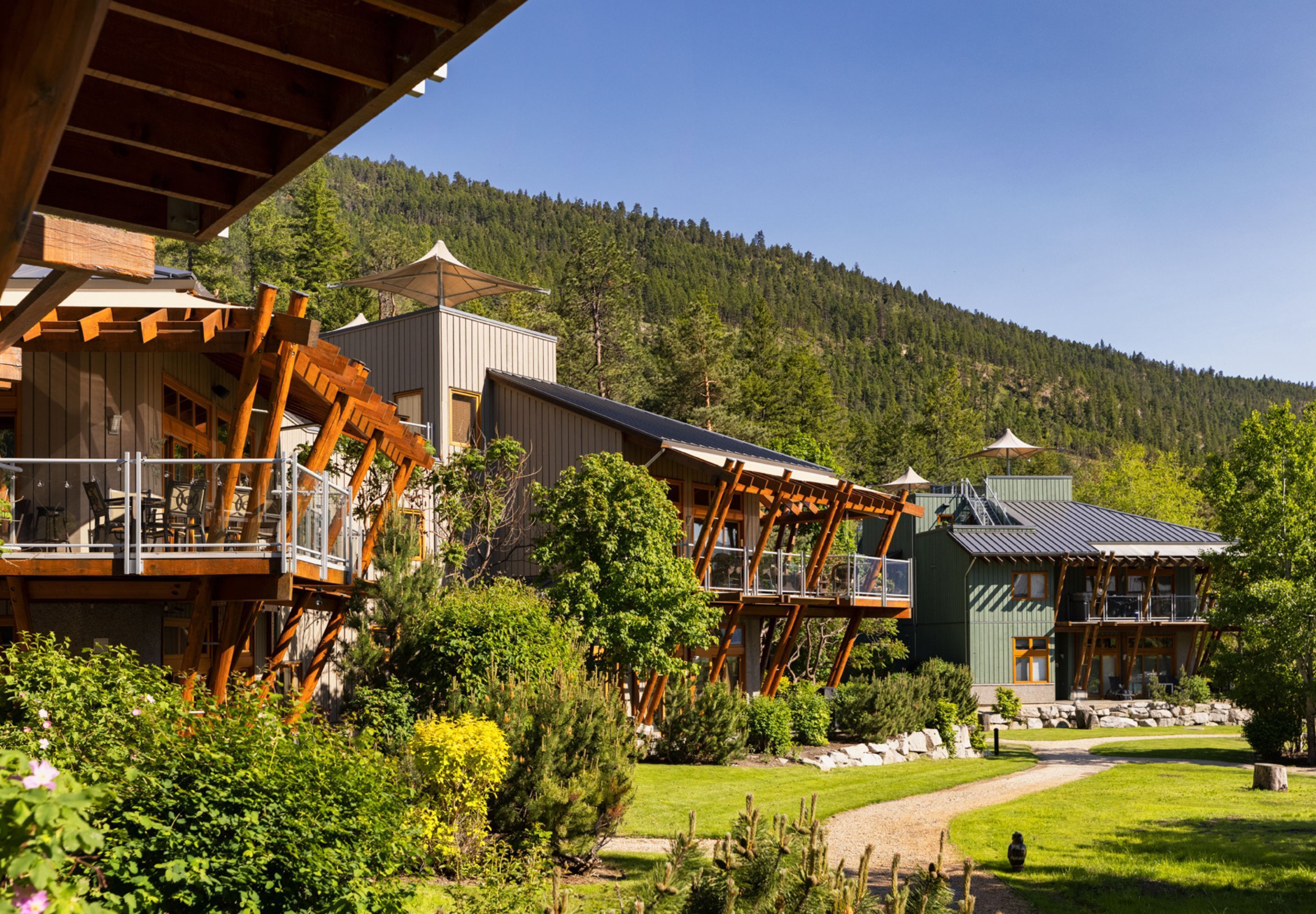 Un resort con varias edificaciones, zonas de estar al aire libre y montañas al fondo.