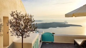 A balcony with a view of the sea and islands, a small tree, and a blue gate. - Dreams Luxury Suites (Santorini)