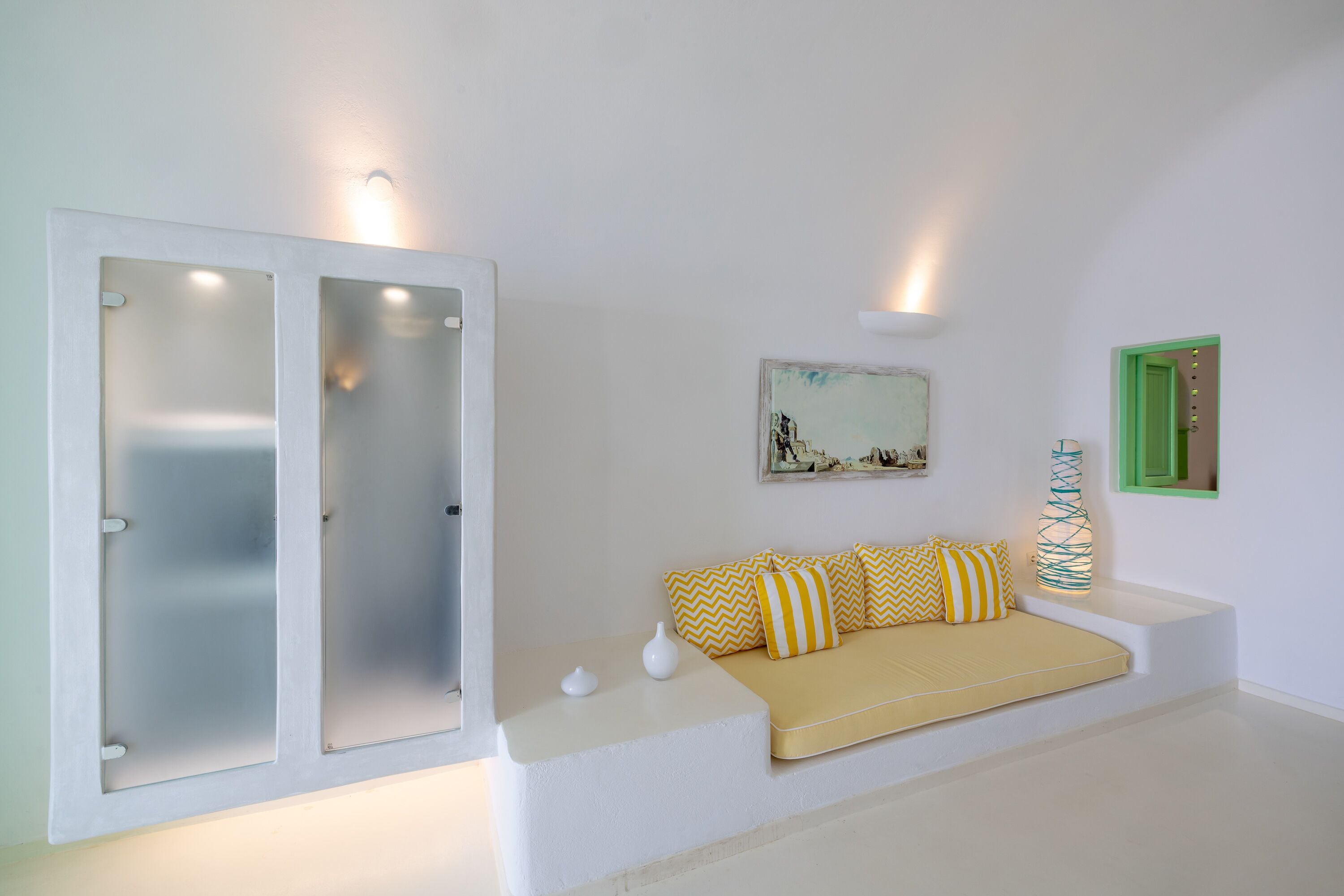 A minimalist room with a sofa, a painting, and a green door.