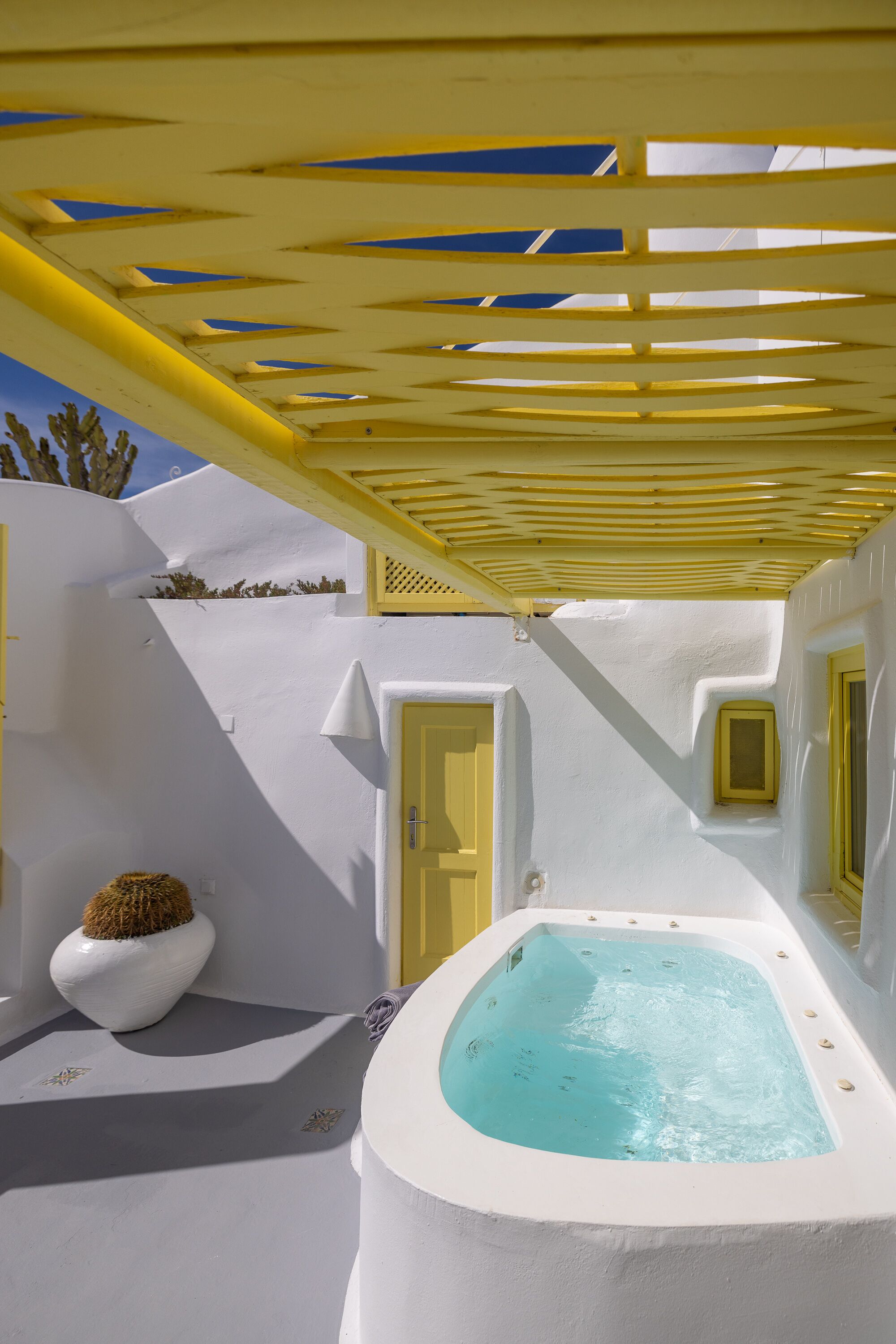 Un bâtiment aux murs blancs, doté d’un jacuzzi, d’une porte et d’une petite fenêtre.