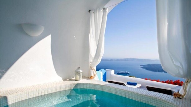 A clear view of a swimming pool with a view of the sea and a white building. - Dreams Luxury Suites (Santorini)