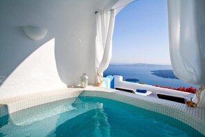 A clear view of a swimming pool with a view of the sea and a white building. - Dreams Luxury Suites (Santorini)
