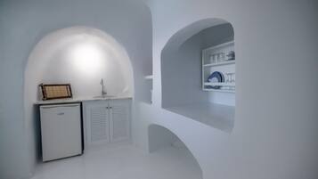 Cocina minimalista con refrigerador empotrado, lavamanos y repisa con cristalería.