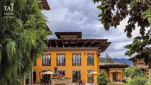 A traditional Bhutanese building with a courtyard and a pond.