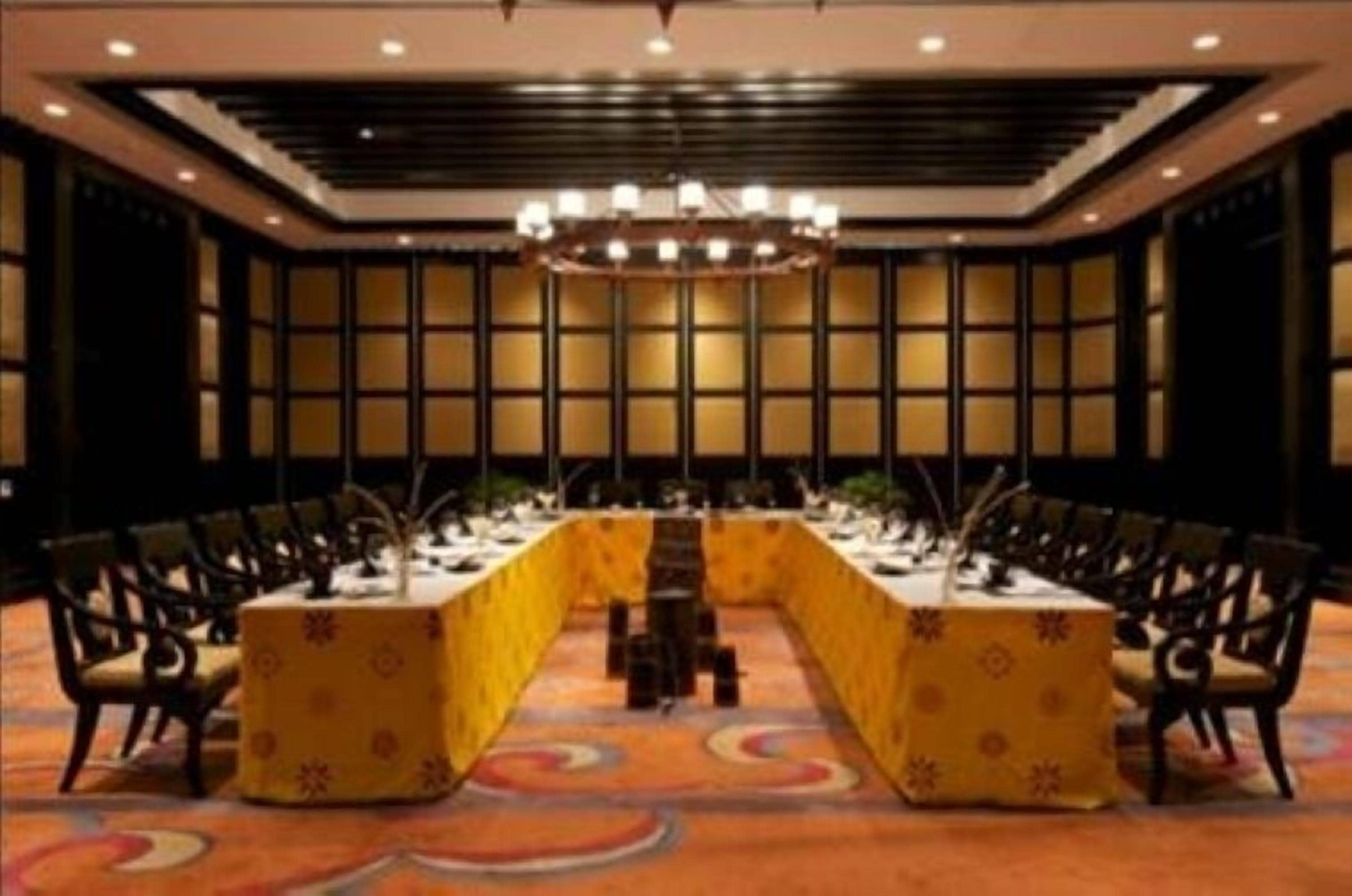 Une salle de conférence avec une longue table, des chaises et un lustre.