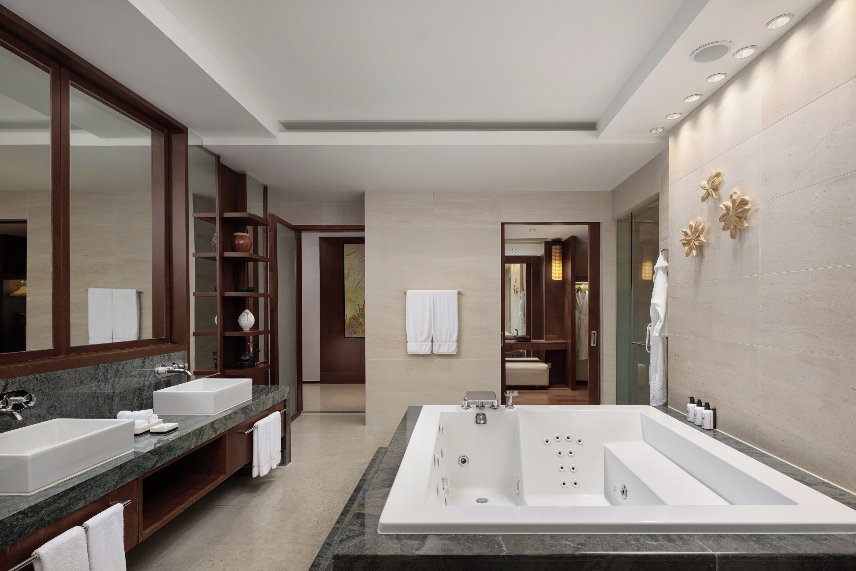A modern bathroom with a large bathtub, two sinks, and a vanity with a mirror.