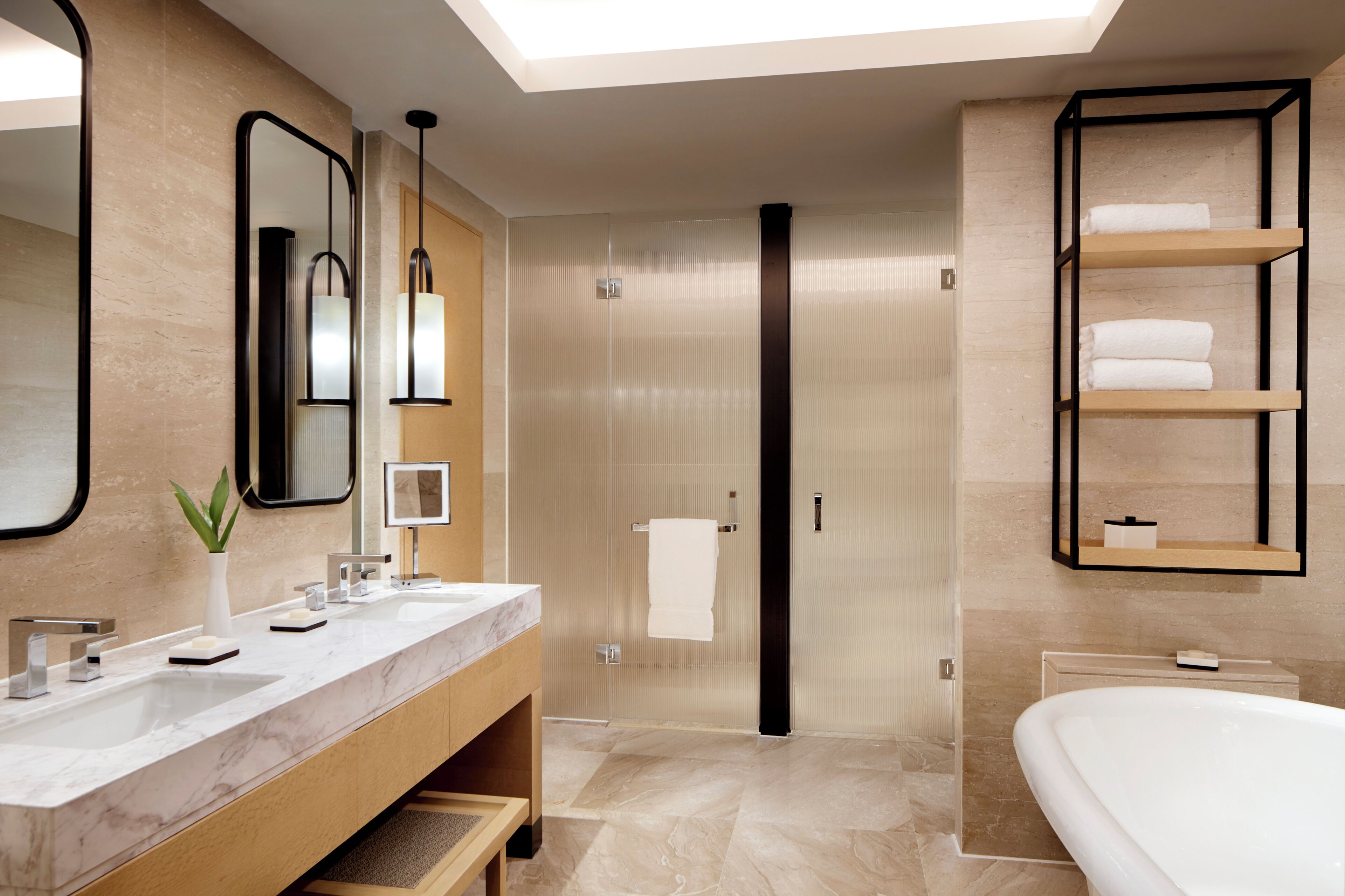 Une salle de bain moderne dotée d’un grand miroir, de deux lavabos, d’une baignoire et d’un espace douche.