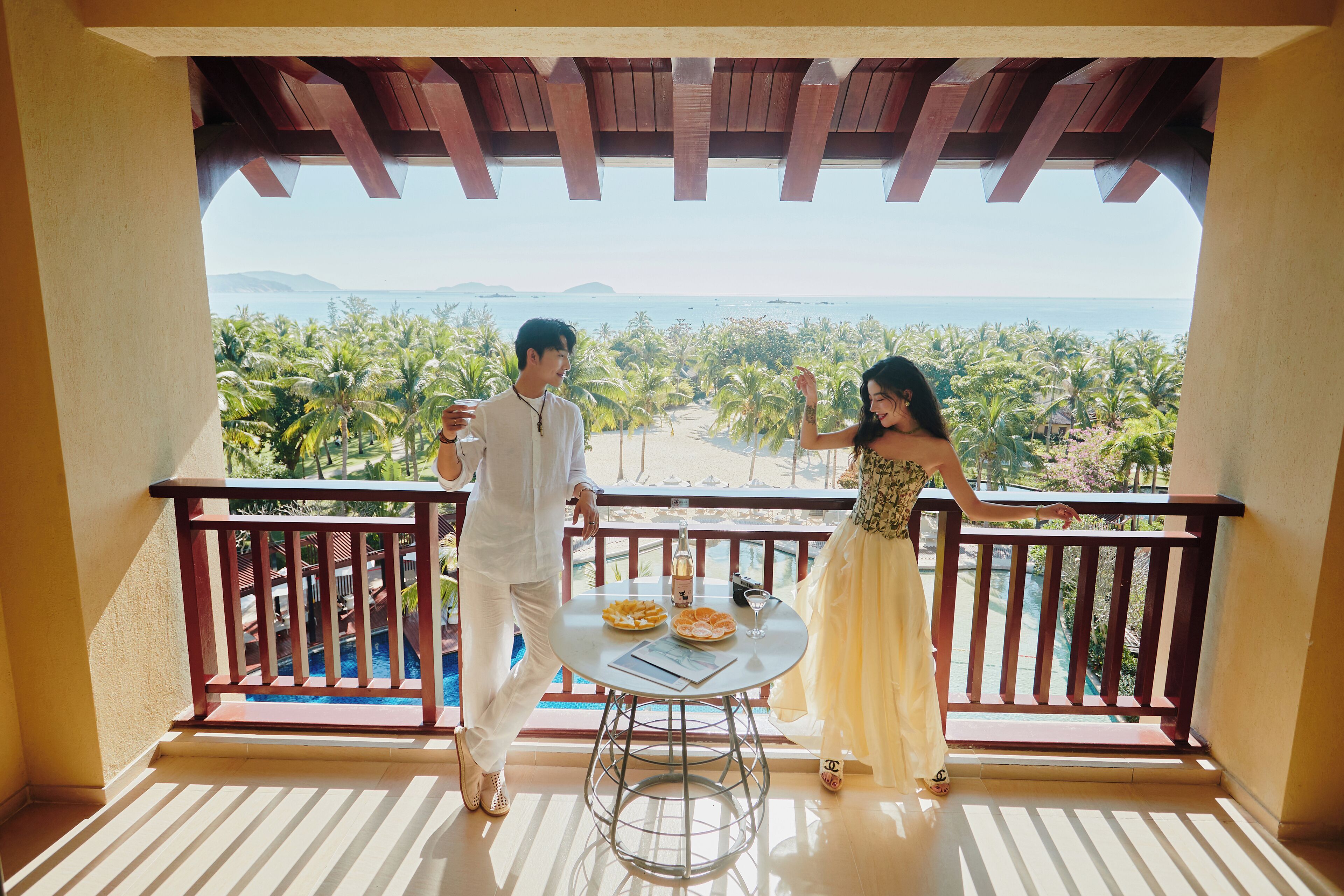 A balcony with a view of palm trees and the ocean.