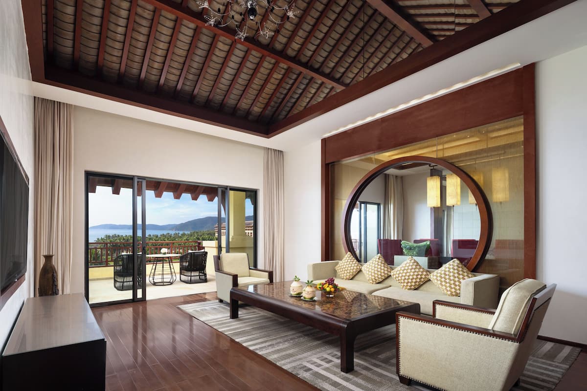 A spacious living area with a large mirror, comfortable seating, and a view through glass doors.