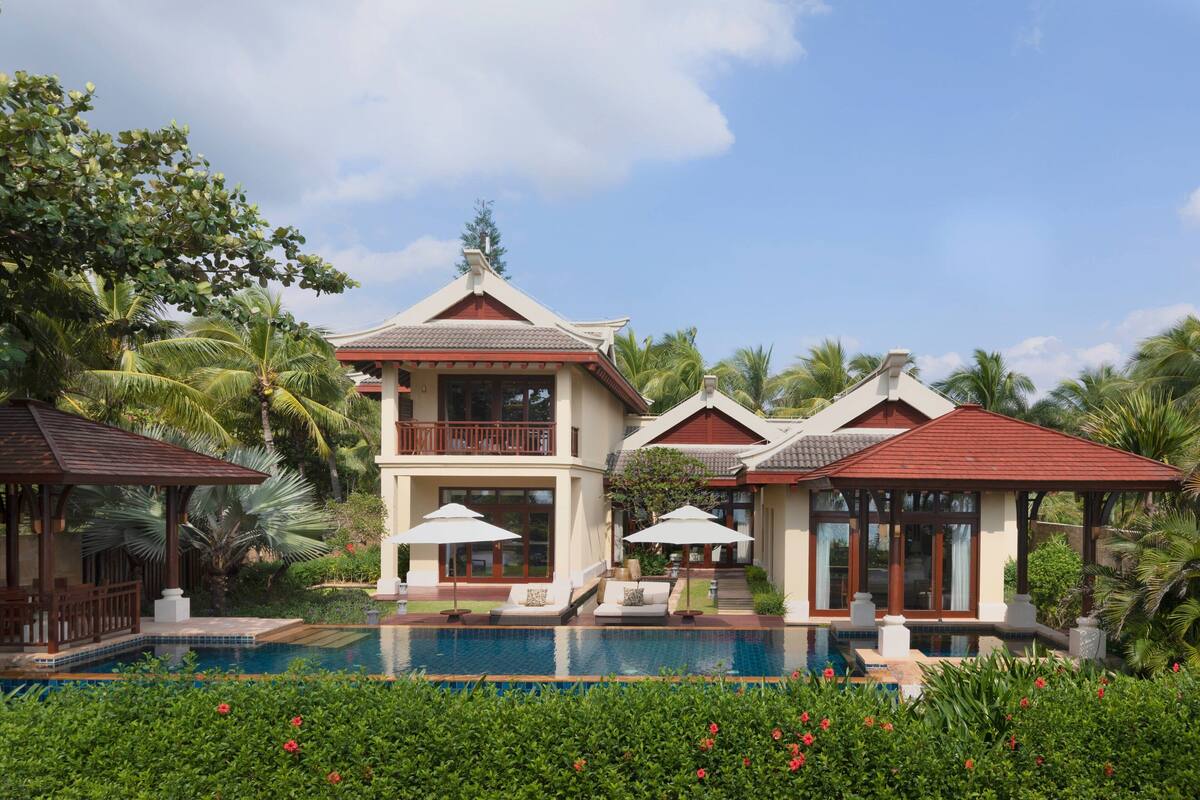 A two-story resort with a swimming pool, lounge chairs, and a gazebo.