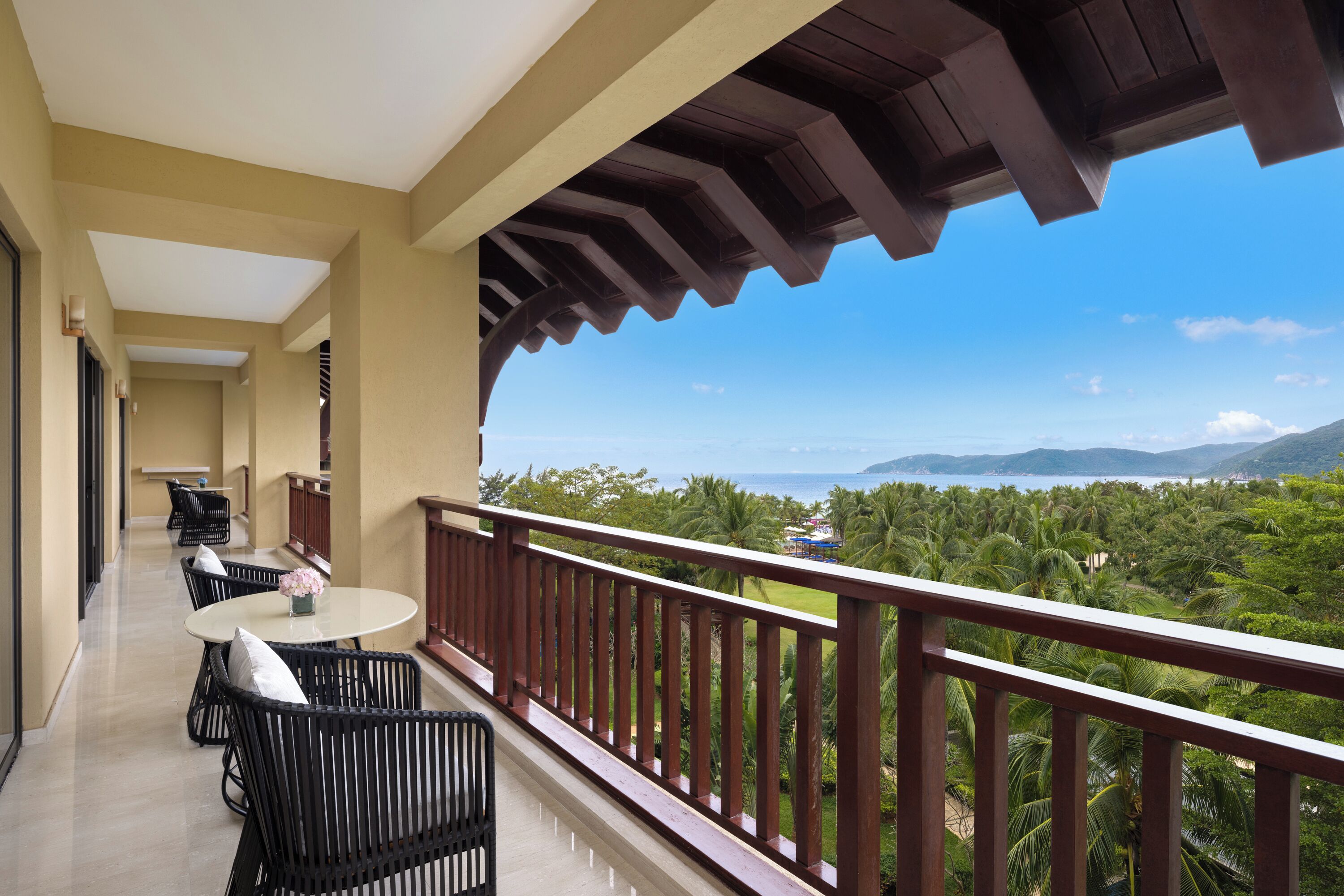 A balcony with a view of a tropical landscape, including palm trees and mountains.